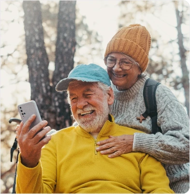Elderly couple at the park looking at the cellphone and smiling